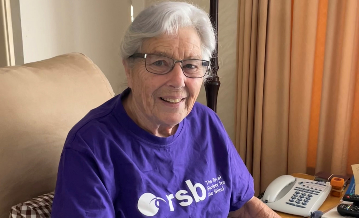 Jean smiling at the camera. She is wearing a purple RSB top