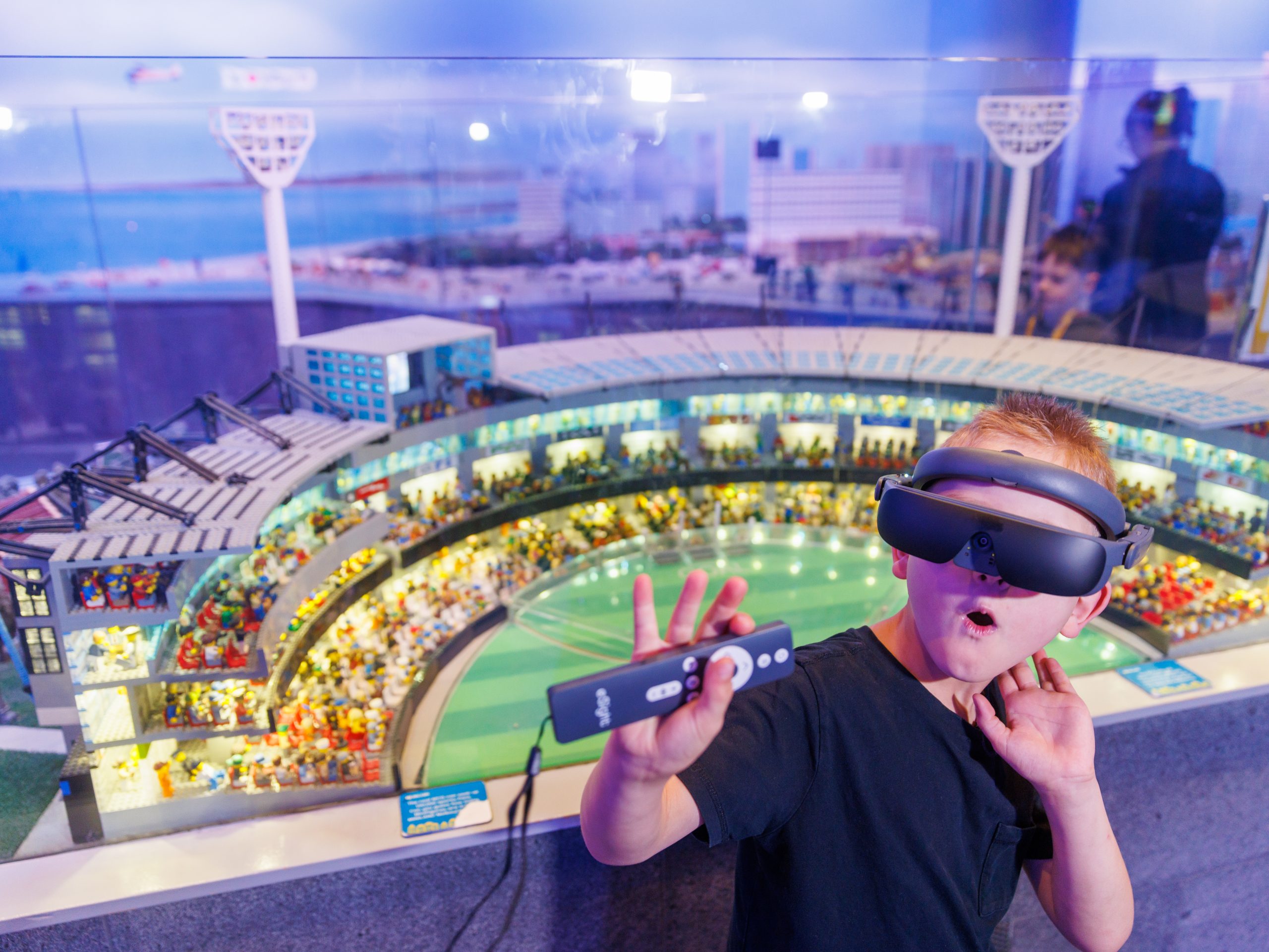 Ethan wearing an eSight 4 device. Stadium replica made from lego in foreground.