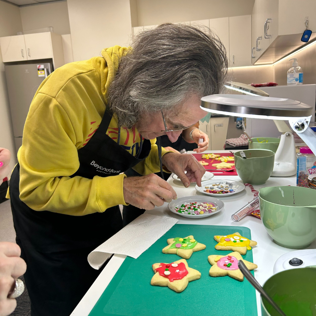 A man in a yellow top is decorating cookies