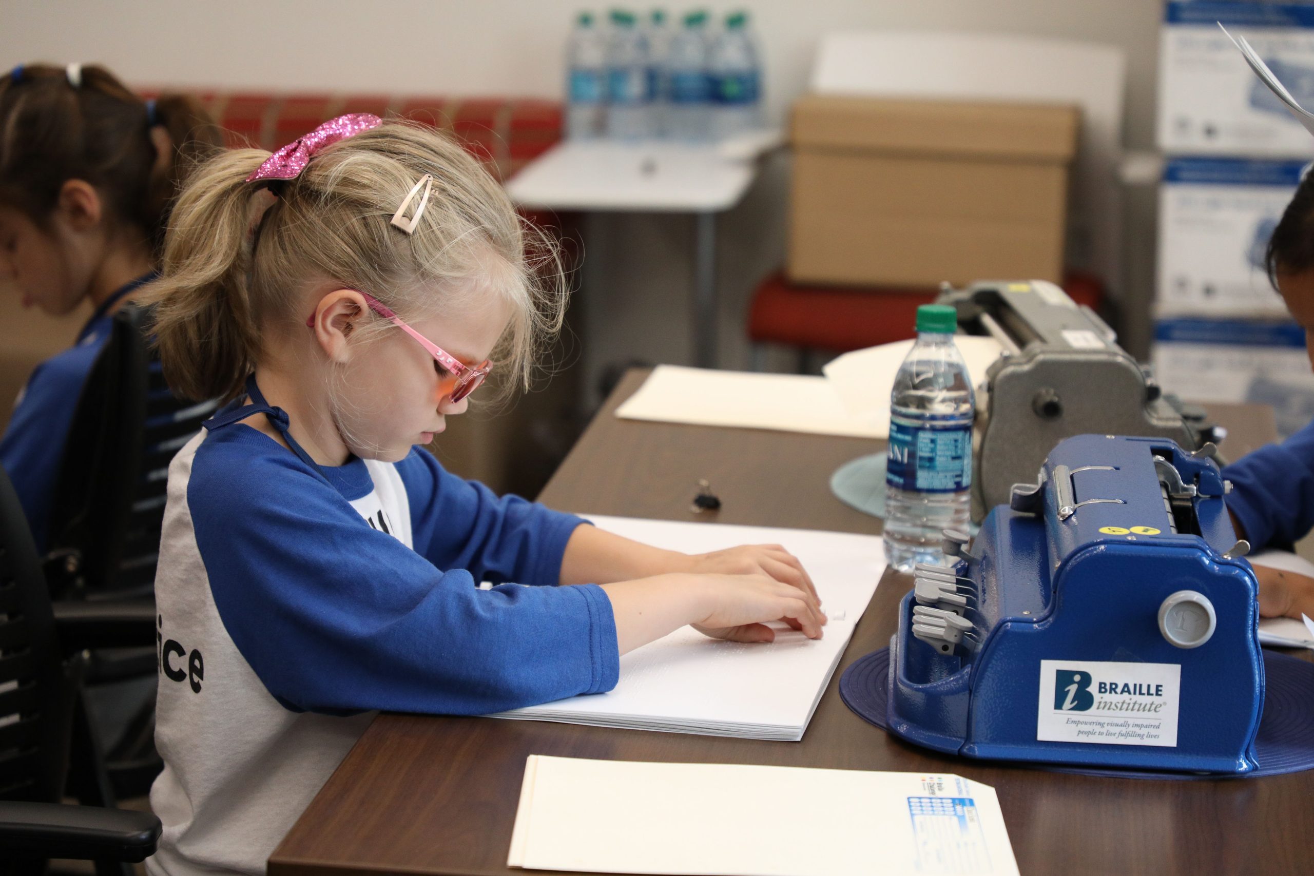 young blonde girl sitting tracing braille with her fingers